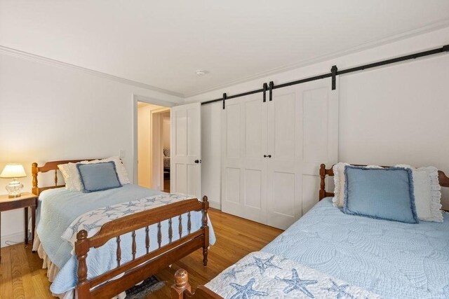 307 Riverview Dr, Chatham, MA 02633 - bedroom featuring a closet, a barn door, crown molding, and light wood-type flooring