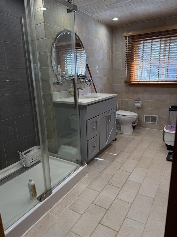 127 Sumner St, Milton, MA 02186 - bathroom with tile walls, toilet, a stall shower, and vanity