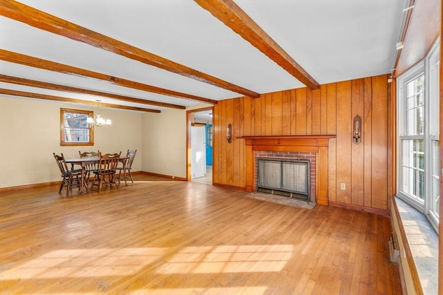 living room with light hardwood / wood-style floors, beam ceiling, a notable chandelier, and a fireplace