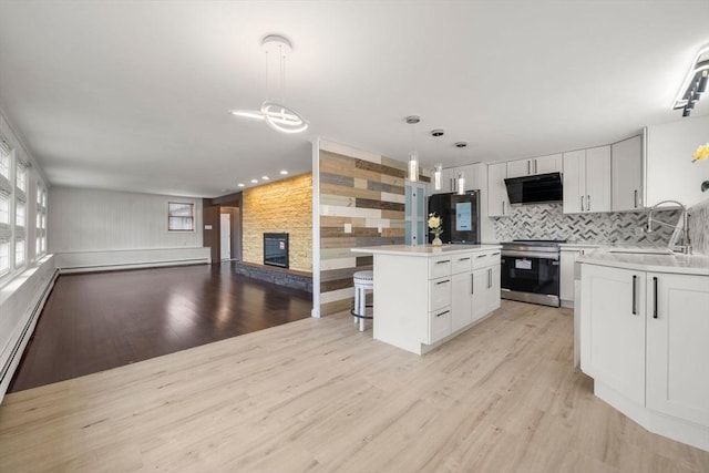 152 Audubon Ave, Braintree, MA 02184 - kitchen with stainless steel stove, a sink, exhaust hood, open floor plan, and a kitchen bar