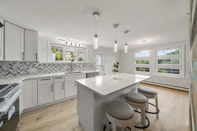 152 Audubon Ave, Braintree, MA 02184 - kitchen with a sink, stove, a baseboard heating unit, light countertops, and tasteful backsplash