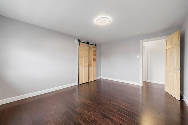 152 Audubon Ave, Braintree, MA 02184 - unfurnished bedroom with a barn door, dark wood finished floors, and baseboards
