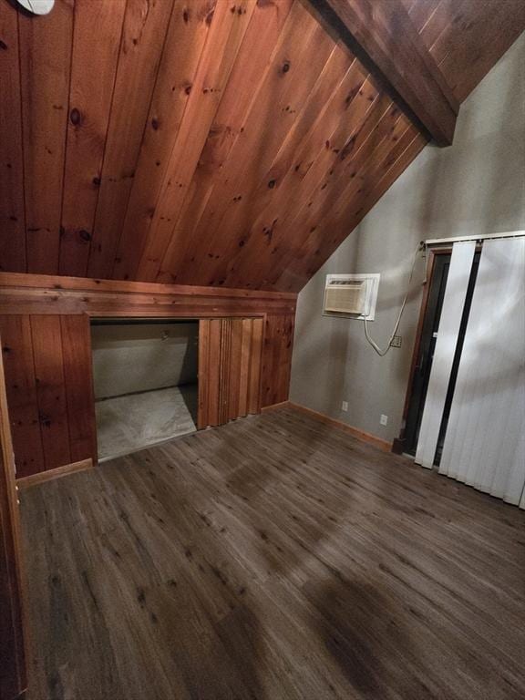 additional living space with dark hardwood / wood-style flooring, wood ceiling, a wall unit AC, and lofted ceiling with beams