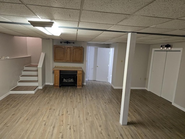 basement with a drop ceiling and light hardwood / wood-style floors