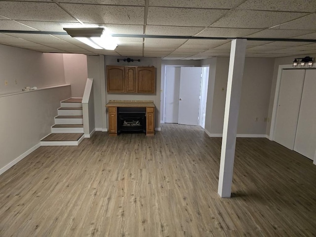 basement with a paneled ceiling and light hardwood / wood-style floors