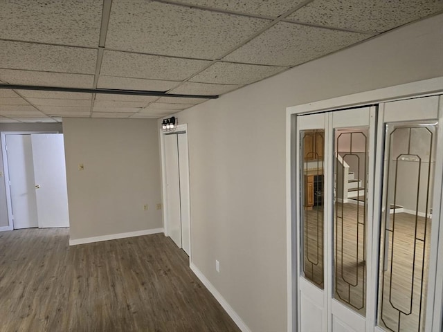 unfurnished room featuring dark wood-type flooring and a drop ceiling