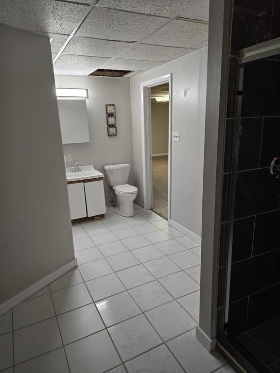 bathroom with vanity, toilet, a shower, and a drop ceiling