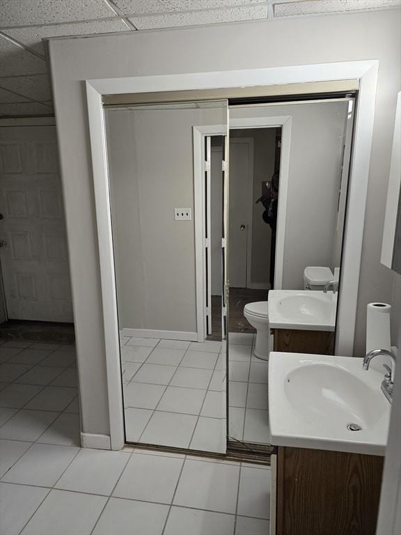 bathroom with vanity, a drop ceiling, tile patterned floors, and toilet