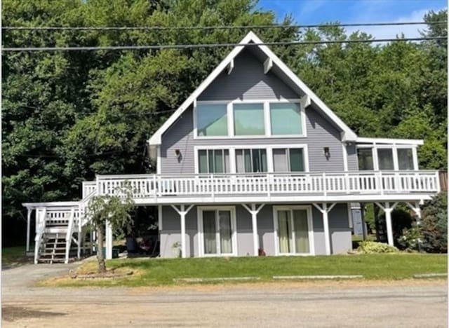 rear view of house with a wooden deck and a lawn