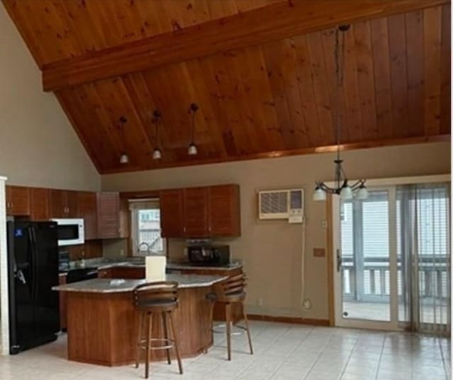 kitchen with a wall mounted air conditioner, beamed ceiling, a breakfast bar area, a center island, and black appliances