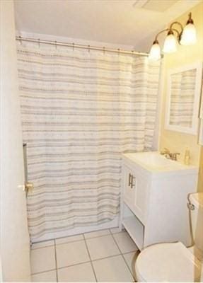 bathroom with tile patterned flooring, a shower with shower curtain, vanity, and toilet