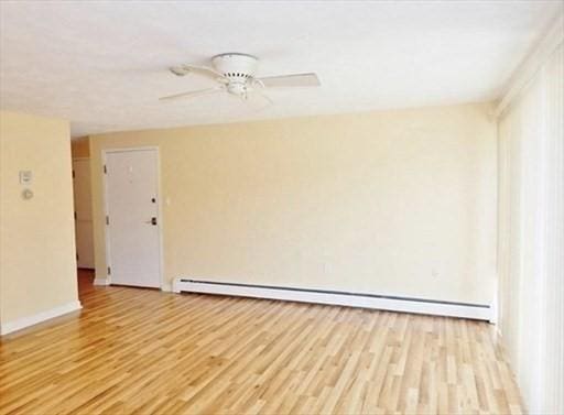 unfurnished room with light wood-type flooring, ceiling fan, baseboards, and baseboard heating