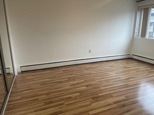 unfurnished room featuring baseboard heating and wood finished floors