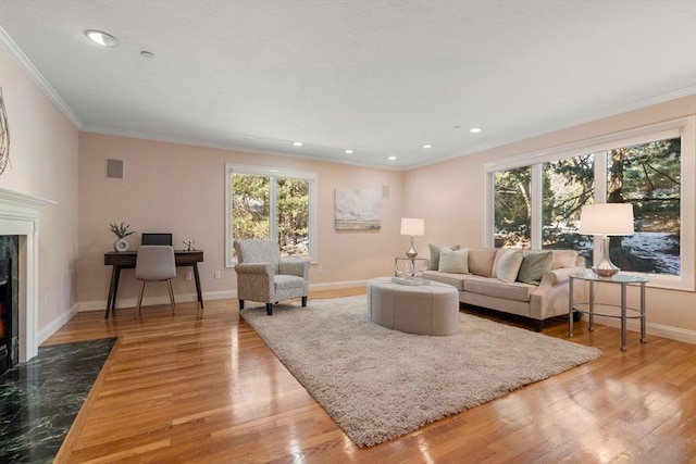 living room with ornamental molding, a fireplace, light hardwood / wood-style floors, and a wealth of natural light