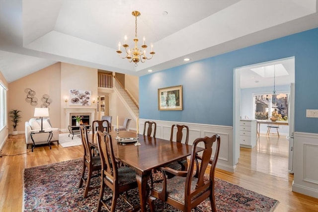 dining room with a chandelier, a raised ceiling, and light wood-type flooring