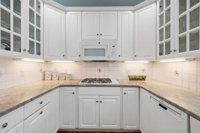 kitchen with white cabinetry, light stone counters, and white appliances