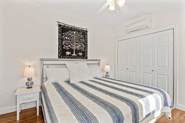 bedroom featuring baseboards, vaulted ceiling, wood finished floors, and a wall mounted AC