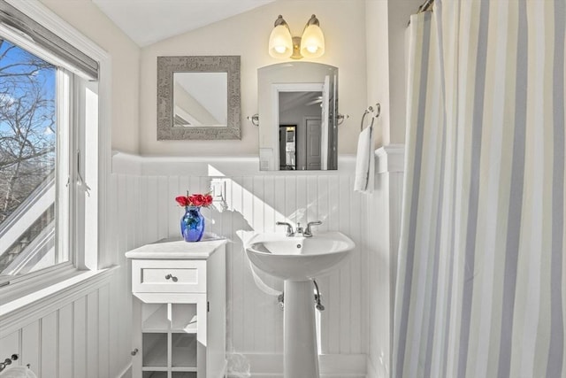 bathroom featuring a wainscoted wall, vaulted ceiling, and a sink