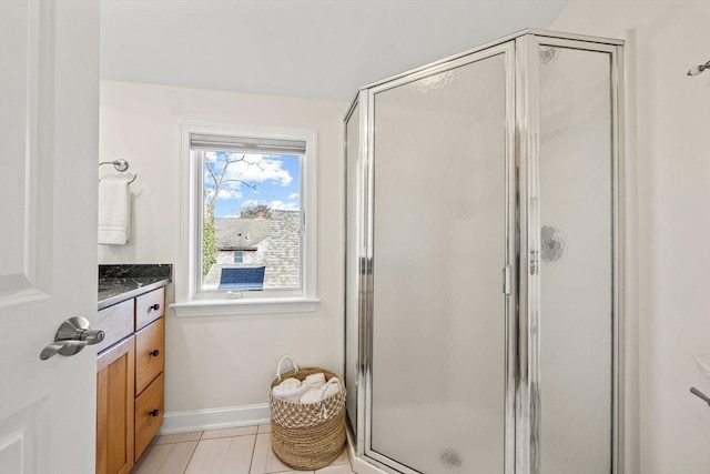 bathroom with a stall shower, tile patterned floors, baseboards, and vanity