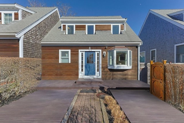 view of front of property featuring a deck and roof with shingles