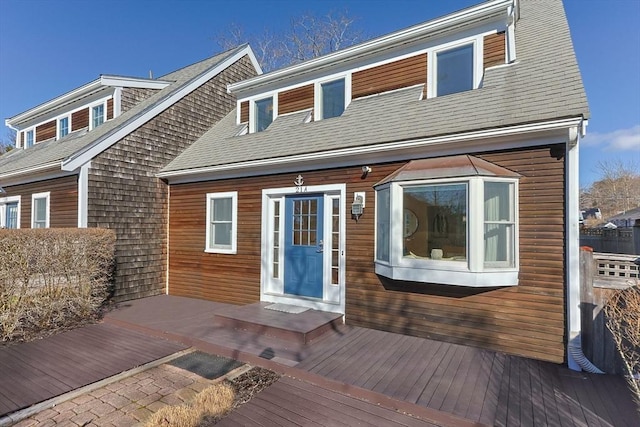 exterior space with roof with shingles and a wooden deck