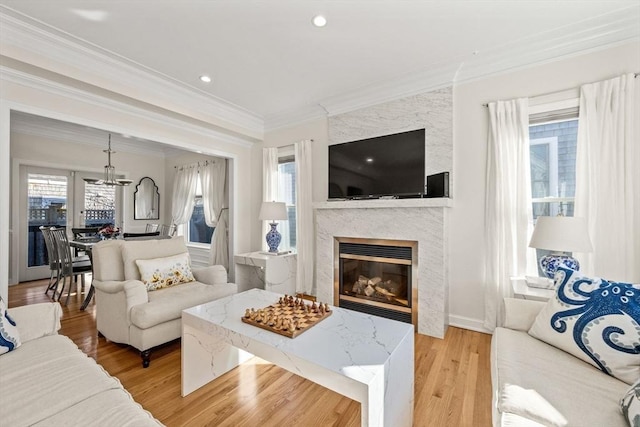 living area with baseboards, light wood-style flooring, a premium fireplace, ornamental molding, and recessed lighting