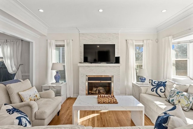 living room with light wood-style flooring, a fireplace, crown molding, and recessed lighting