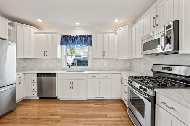 kitchen with light wood-style flooring, white cabinetry, stainless steel appliances, and a sink