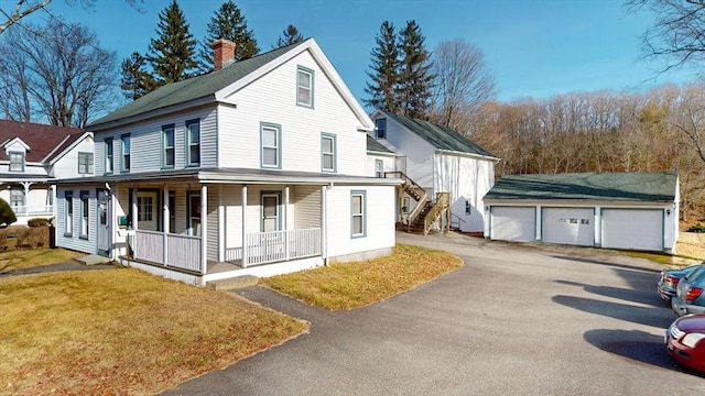 view of front of property featuring a porch, a garage, and an outbuilding