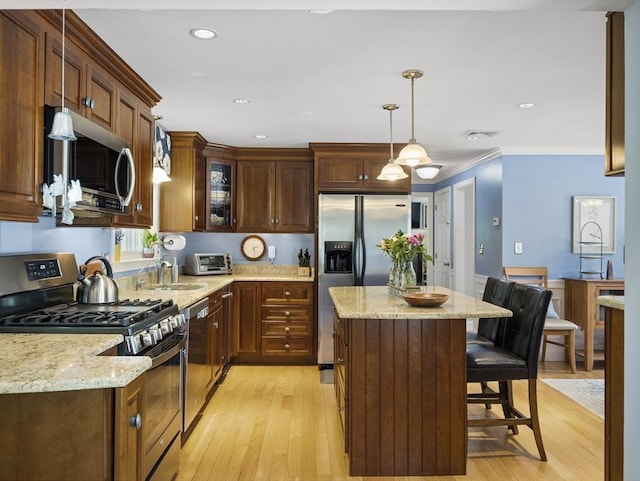 10 Robinhood Rd, Tyngsborough, MA 01879 - kitchen featuring appliances with stainless steel finishes, a center island, a kitchen breakfast bar, a sink, and light wood-type flooring