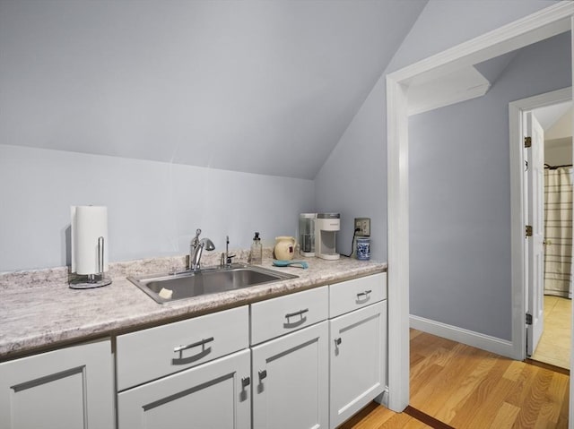 10 Robinhood Rd, Tyngsborough, MA 01879 - kitchen featuring a sink, lofted ceiling, white cabinetry, light countertops, and light wood-style floors