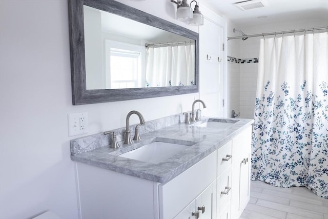 bathroom featuring a shower with curtain, double vanity, visible vents, and a sink