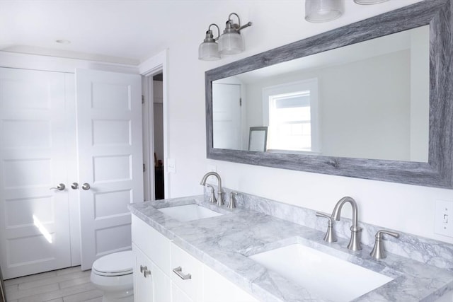 full bathroom featuring double vanity, toilet, and a sink