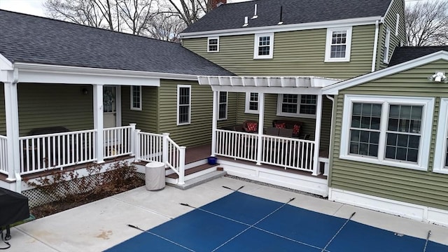 back of property with a patio area, a chimney, covered porch, and roof with shingles