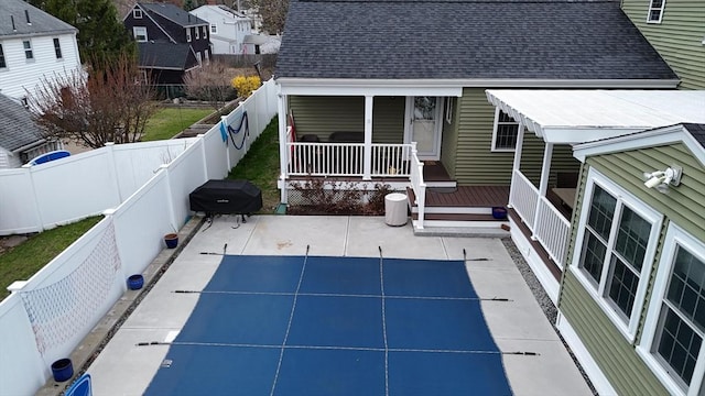 back of property with a fenced backyard, a porch, a patio, and a shingled roof