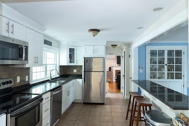 kitchen featuring a kitchen breakfast bar, stainless steel appliances, a sink, arched walkways, and tasteful backsplash