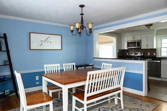 dining room featuring baseboards, a notable chandelier, crown molding, and light wood finished floors