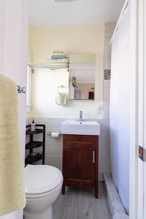 bathroom featuring toilet, tile walls, a shower with curtain, wood-type flooring, and vanity