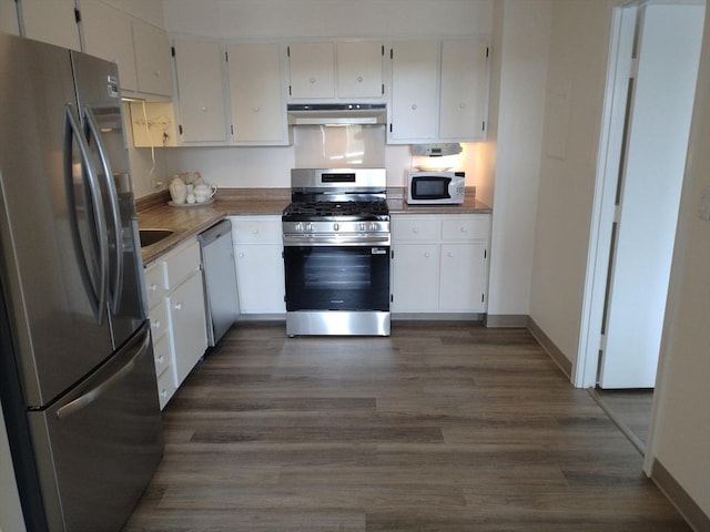 kitchen with dark wood finished floors, under cabinet range hood, white cabinets, and white appliances
