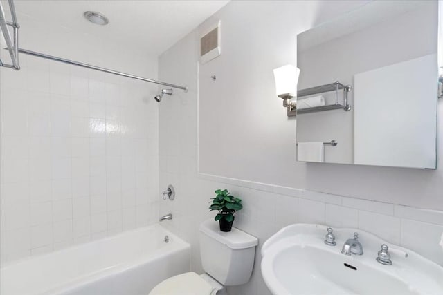 full bath featuring shower / tub combination, a sink, wainscoting, tile walls, and toilet