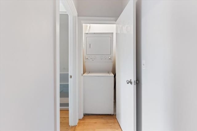 laundry room with laundry area, light wood-style flooring, and stacked washing maching and dryer