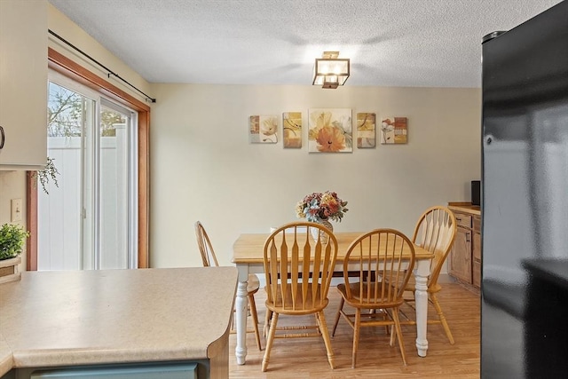 dining room with light wood-style floors and a textured ceiling