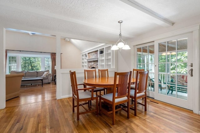 dining space with a textured ceiling, vaulted ceiling with beams, a notable chandelier, wood finished floors, and visible vents