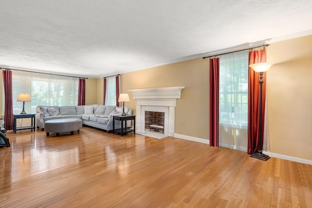 unfurnished living room featuring a fireplace with flush hearth, baseboards, and wood finished floors