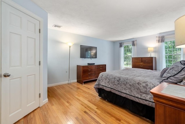 bedroom featuring light wood-type flooring, visible vents, and baseboards