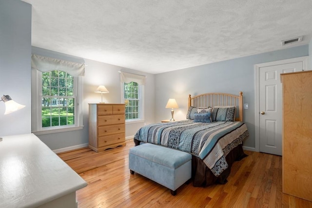 bedroom with baseboards, multiple windows, visible vents, and light wood-style floors