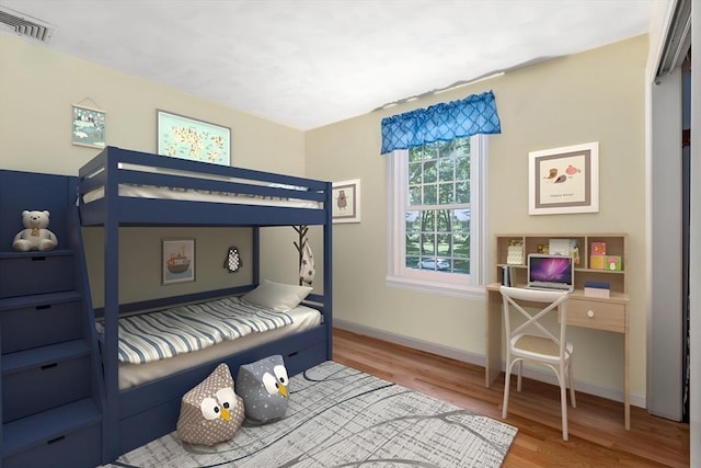 bedroom featuring wood finished floors, visible vents, and baseboards