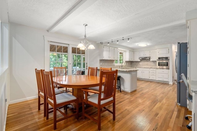 dining space featuring light wood-style floors, a textured ceiling, a wealth of natural light, and an inviting chandelier