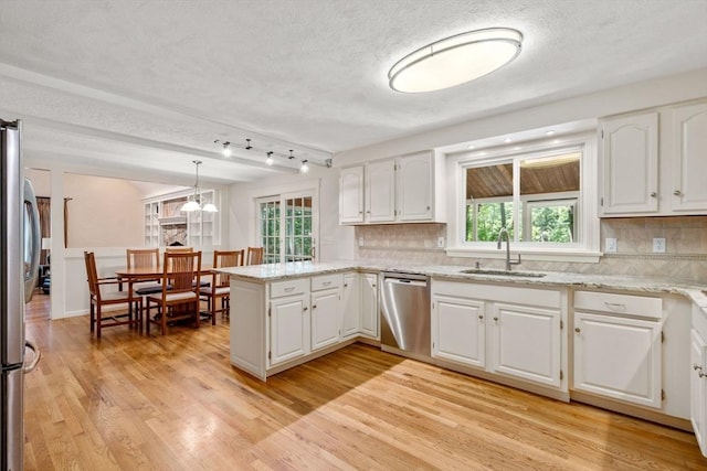 kitchen with stainless steel appliances, a peninsula, a sink, and white cabinetry