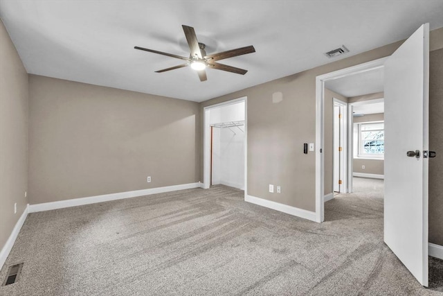 unfurnished bedroom with light carpet, a closet, a spacious closet, and ceiling fan